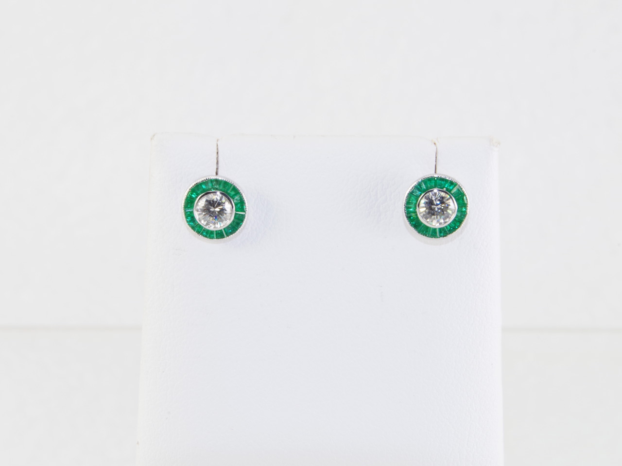 Pair of 14k white gold halo Diamond earring, with two I-J color, VS1-2 clarity, round brilliant cut Diamonds. The Diamonds have a total weight of .51 carat, and are bezel set. In addition, there are thirty-six channel set custom emeralds, with a total wei